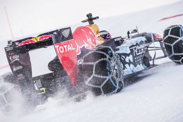 Max Verstappen driving a Red Bull RB7 F1 car on snow rear three quarters